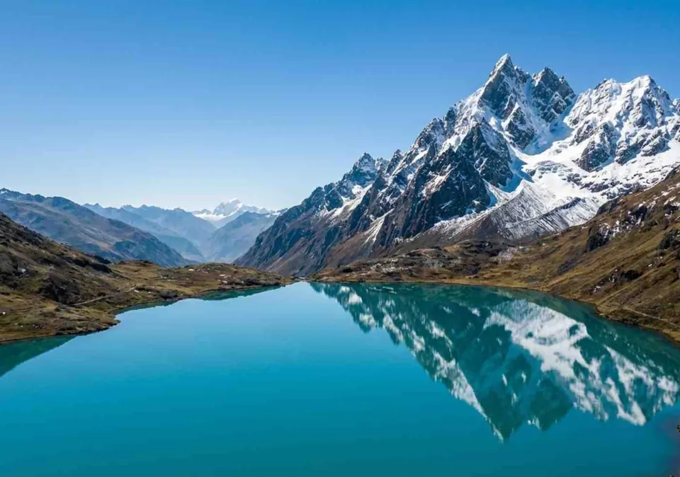 Nevado reflejado en una laguna turquesa bajo un cielo despejado