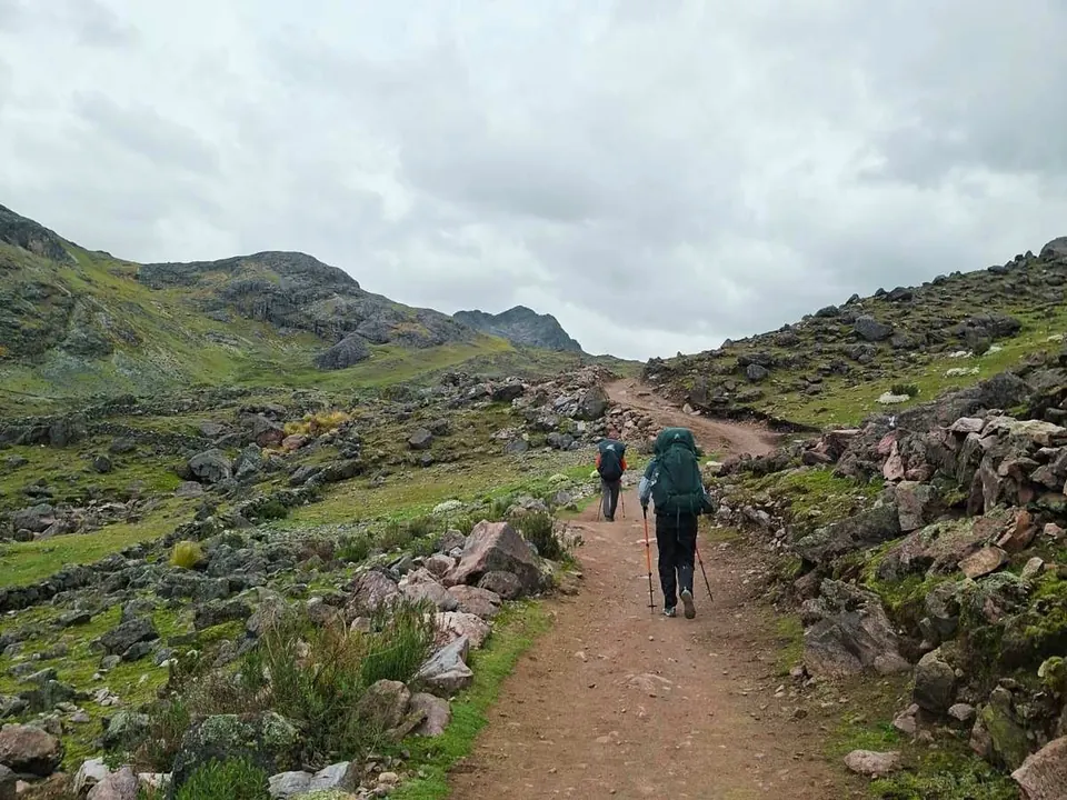 Caminantes con mochila por un sendero de altura hacia el Ausangate